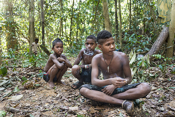Drei Jungen der Orang Asil sitzen auf dem Boden im Dschungel und rauchen  Ureinwohner  indigenes Volk  tropischer Regenwald  Nationalpark Taman Negara  Malaysia  Asien