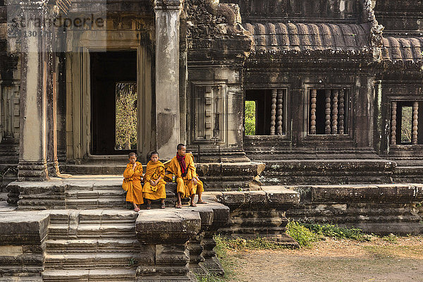 Mönche  Novizen  sitzen vor einer Bibliothek am westlichen Zugangsweg  Tempel Angkor Wat  Provinz Siem Reap  Kambodscha  Asien