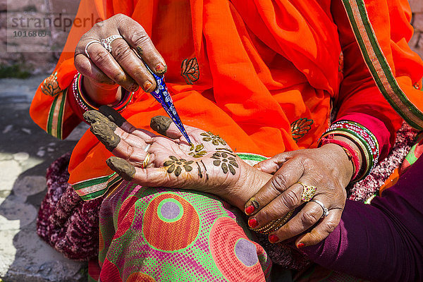 Eine indische Frau bemalt eine Hand mit Henna  vor dem Badrinath-Tempel  Char Dham Pilgerort  Badrinath  Uttarakhand  Indien  Asien