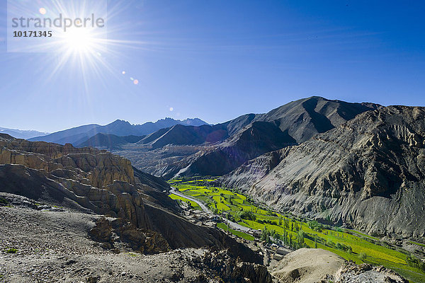 Karge Landschaft  grüne Wiesen und blauer Himmel am Dorf Lamayuru  Moonlands  Mondlandschaft hinten  Lamayuru  Jammu und Kaschmir  Indien  Asien