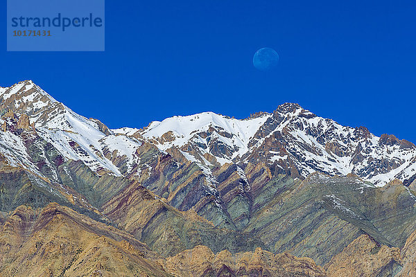Schneebedeckte  farbenfrohe Berge mit dem aufgehenden Mond  Lamayuru  Jammu und Kaschmir  Indien  Asien