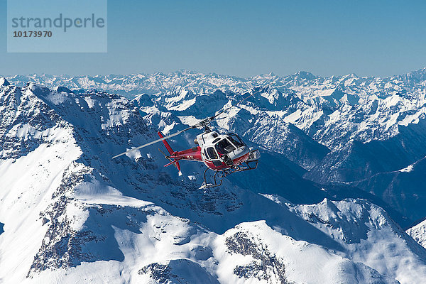 Helikopter im Flug vor Bergpanorama im Winter  Schweizer Alpen  Engadin  Graubünden  Schweiz  Europa