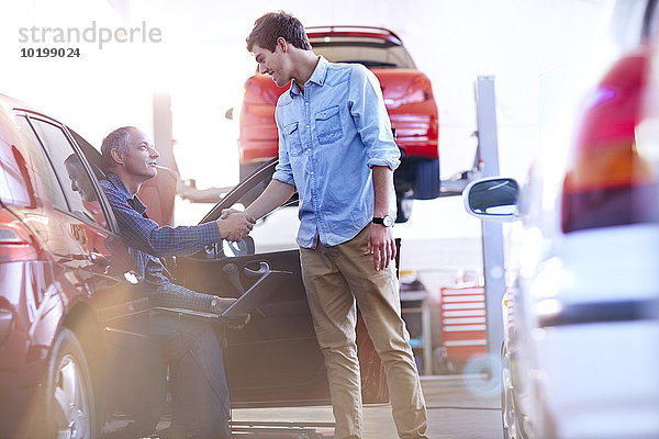 Mechaniker- und Kunden-Handshake in der Kfz-Werkstatt