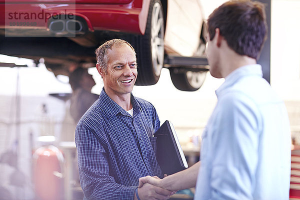 Mechaniker- und Kunden-Handshake in der Kfz-Werkstatt