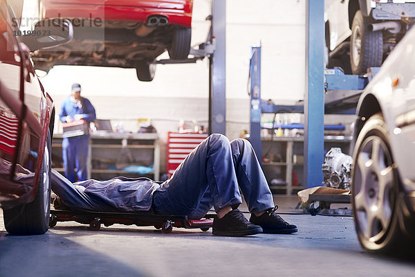 Mechaniker unter dem Auto in der Autowerkstatt