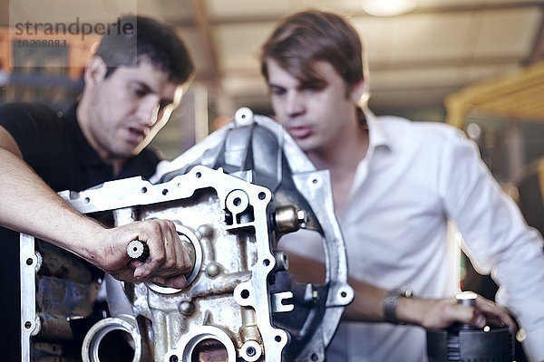 Mechaniker prüfen Teil in der Kfz-Werkstatt