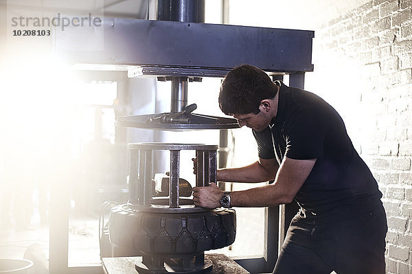 Mechaniker mit Reifenmontiermaschine in der Kfz-Werkstatt