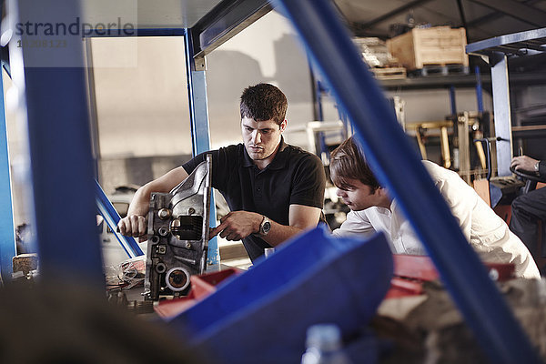 Mechaniker prüfen Teil in der Kfz-Werkstatt