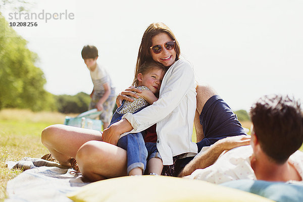 Familie entspannt auf der Decke im sonnigen Feld