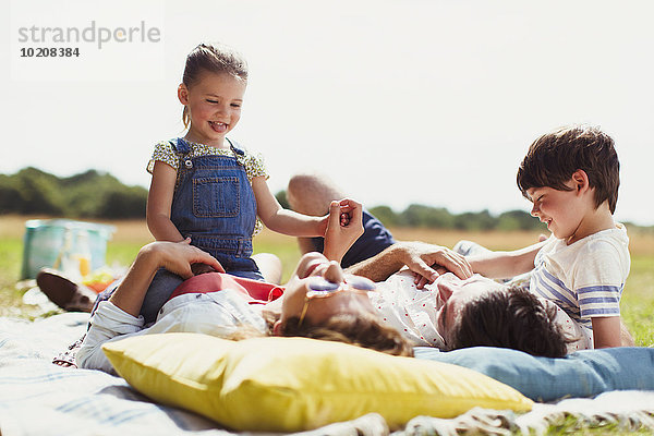 Familie entspannt auf der Decke im sonnigen Feld