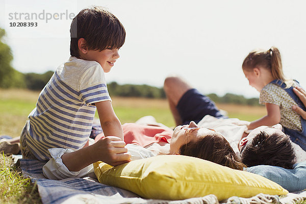 Familie entspannt auf der Decke im sonnigen Feld