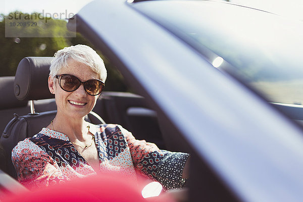 Portrait lächelnde Seniorin mit Sonnenbrille im Cabriolet