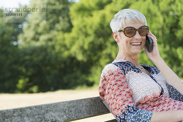 Lächelnde Seniorin am Handy im Park