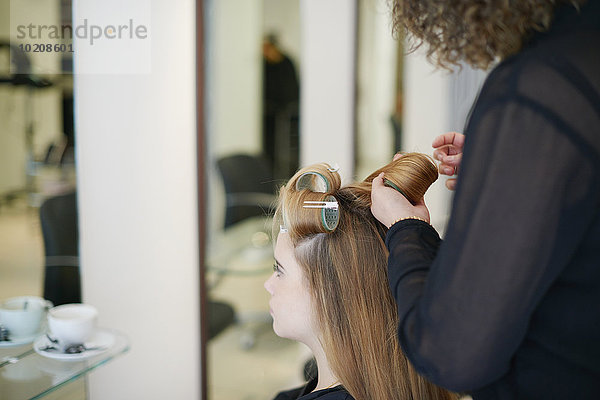 Friseur rollende Kundenhaare in Lockenwicklern im Salon