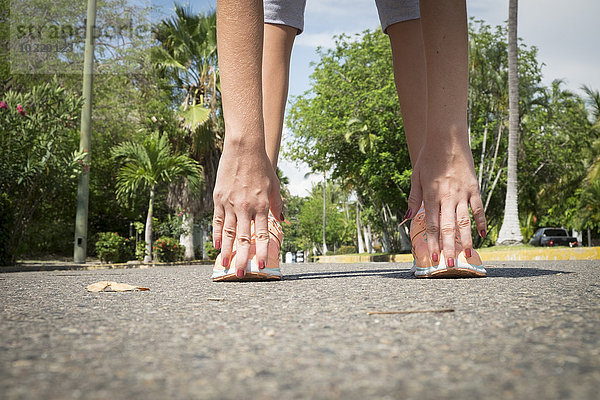 Mexiko  Nayarit  Hände und Füße eines Teenagermädchens beim Stretching auf der Straße