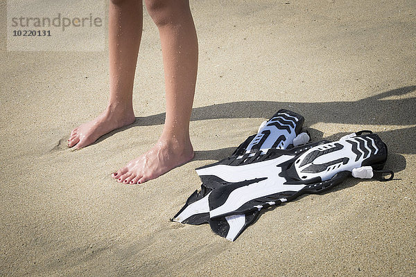 Mexiko  Nayarit  Beine von Teenagermädchen und Flossen am Sandstrand