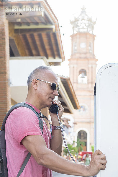 Mexiko  Puerto Vallarta  Tourist mit öffentlichem Telefon vor der Kirche Unserer Lieben Frau von Guadalupe