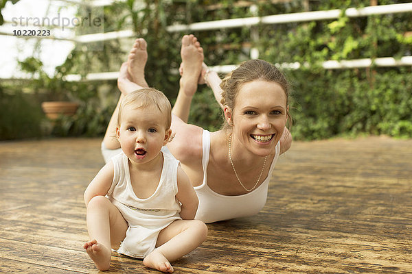 Porträt eines Babys  das vor der Mutter sitzt und Yoga-Übungen macht