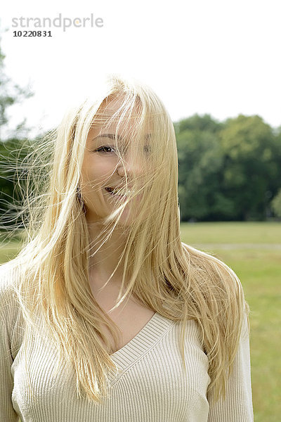 Porträt einer lächelnden blonden Frau mit wehendem Haar