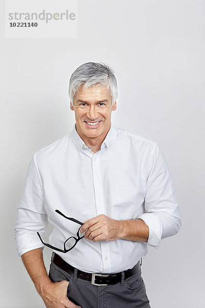 Porträt eines lächelnden reifen Mannes mit Brille in der Hand