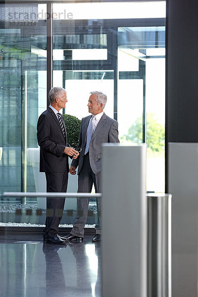 Zwei Geschäftsleute sprechen in der Büro-Lobby