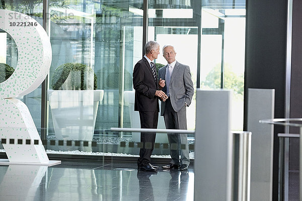 Zwei Geschäftsleute sprechen in der Büro-Lobby