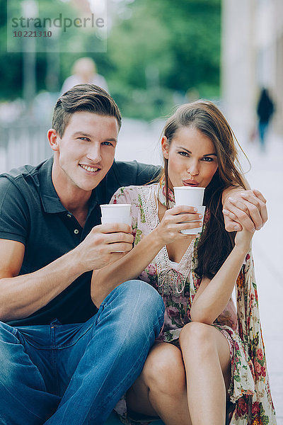 Lächelndes junges Paar trinkt Kaffee im Freien