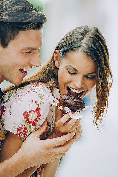 Glückliches junges Paar beim Essen von Schokoladenmuffin