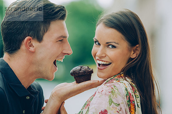 Glückliches junges Paar mit Schokoladenmuffin im Freien