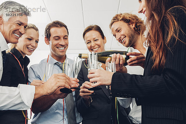 Gruppe von Geschäftsleuten  die im Büro einen Toast mit Champagner ausbringen.