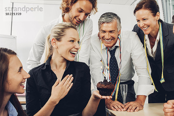 Lächelnde Führungskraft feiert Geburtstag im Büro mit Kollegen