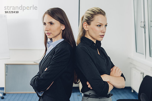 Zwei junge Geschäftsfrauen  die Rücken an Rücken stehen.