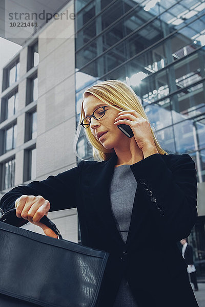 Geschäftsfrau beim Telefonieren außerhalb des Bürogebäudes