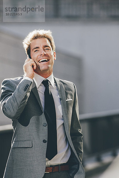 Lächelnder Geschäftsmann beim Telefonieren im Freien