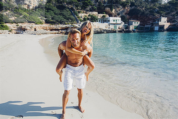 Spanien  Mallorca  Mann huckepack mit seiner Freundin am Meer