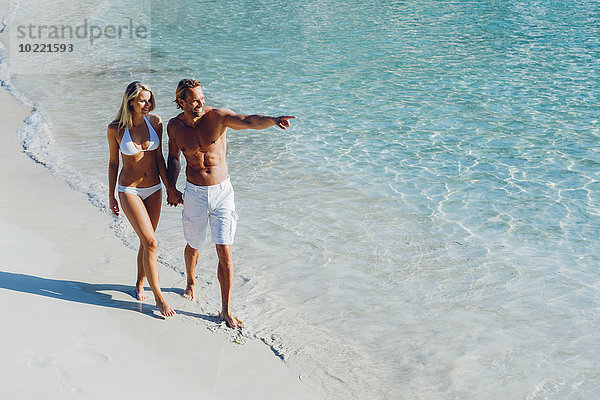 Spanien  Mallorca  Paar  das mit dem Mann am Strand spazieren geht.