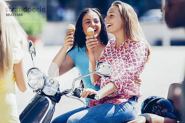 Zwei Teenagermädchen mit Motorroller und Eistüten