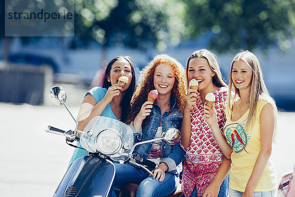 Gruppenbild von vier Freunden mit Motorroller und Eistüten