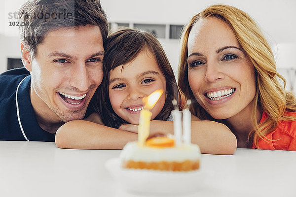 Familie mit Tochter feiert Geburtstag mit Kerzen auf Kuchen