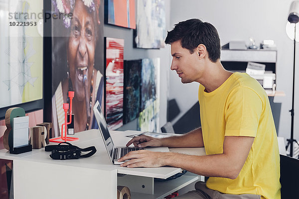 Junger Mann am Schreibtisch mit Laptop