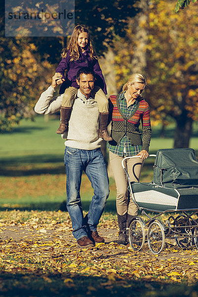 Familie mit Kinderwagen beim Spaziergang im Herbstpark