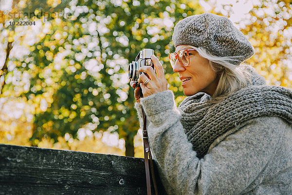 Frau fotografiert mit einer alten Kamera in einem herbstlichen Park