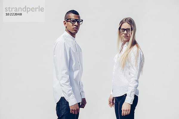 Porträt eines stilvollen jungen Paares in passender Kleidung vor weißem Hintergrund