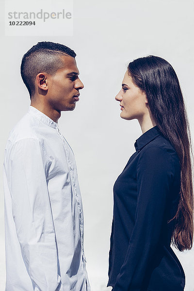 Stilvolles junges Paar von Angesicht zu Angesicht vor weißem Hintergrund