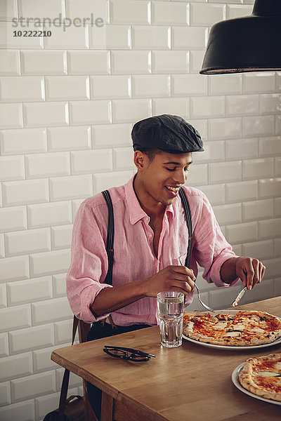 Junger Mann beim Pizzaessen im Restaurant