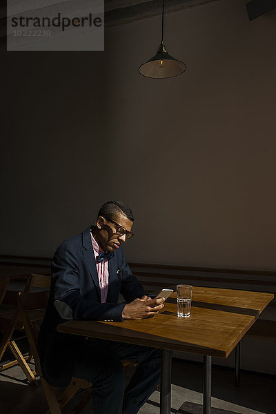 Junger Mann sitzt im Cafe  wartet auf jemanden  liest SMS