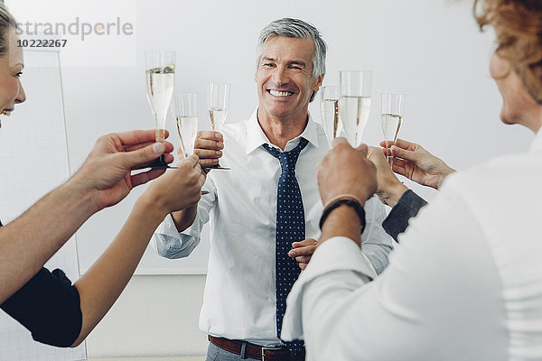 Gruppe von Geschäftsleuten  die im Büro einen Toast mit Champagner ausbringen.