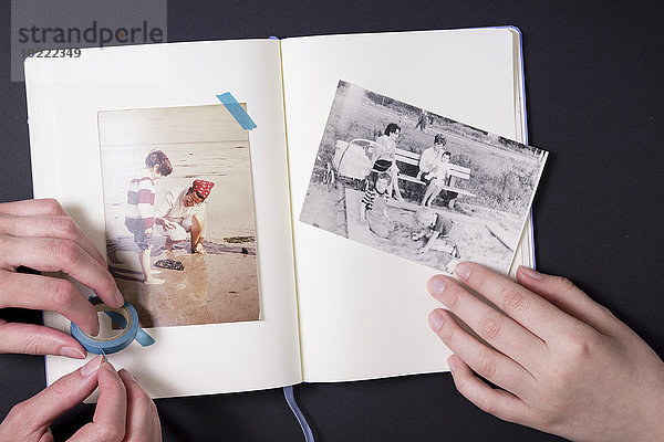 Zwei Leute  die alte Fotos in ein Album kleben.