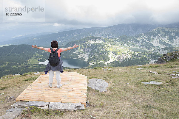 Bulgarien  Rila-Gebirge  Rückansicht der älteren Frau mit ausgestreckten Armen mit Blick auf die Ansicht