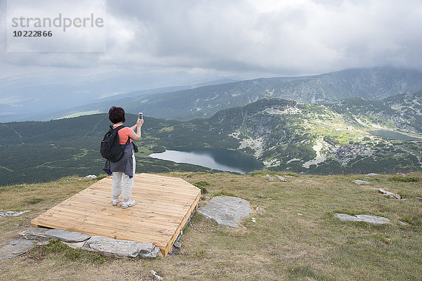 Bulgarien  Rila-Gebirge  Rückansicht der älteren Frau beim Fotografieren mit dem Smartphone